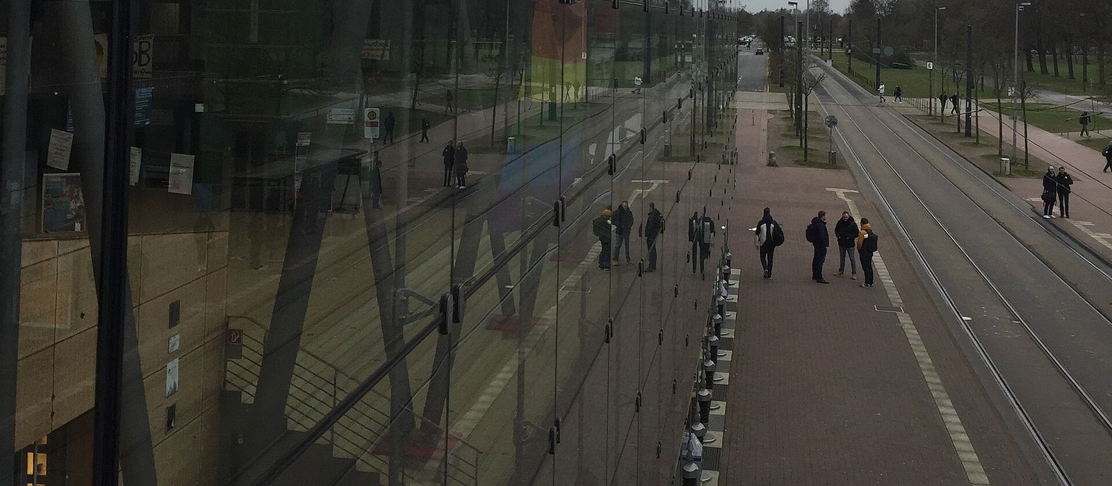 Bremen Üniversitesi kampüsünde cam cepheli Glashaus binası ve önündeki kampüs bulvarında yürüyen öğrenciler
